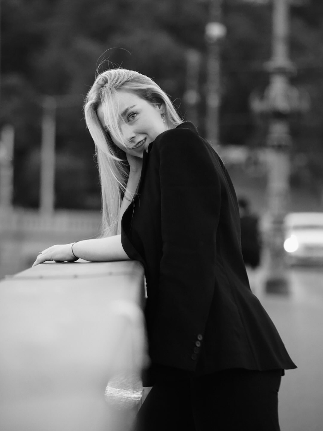 Black and white portrait of a woman leaning on a bridge railing
