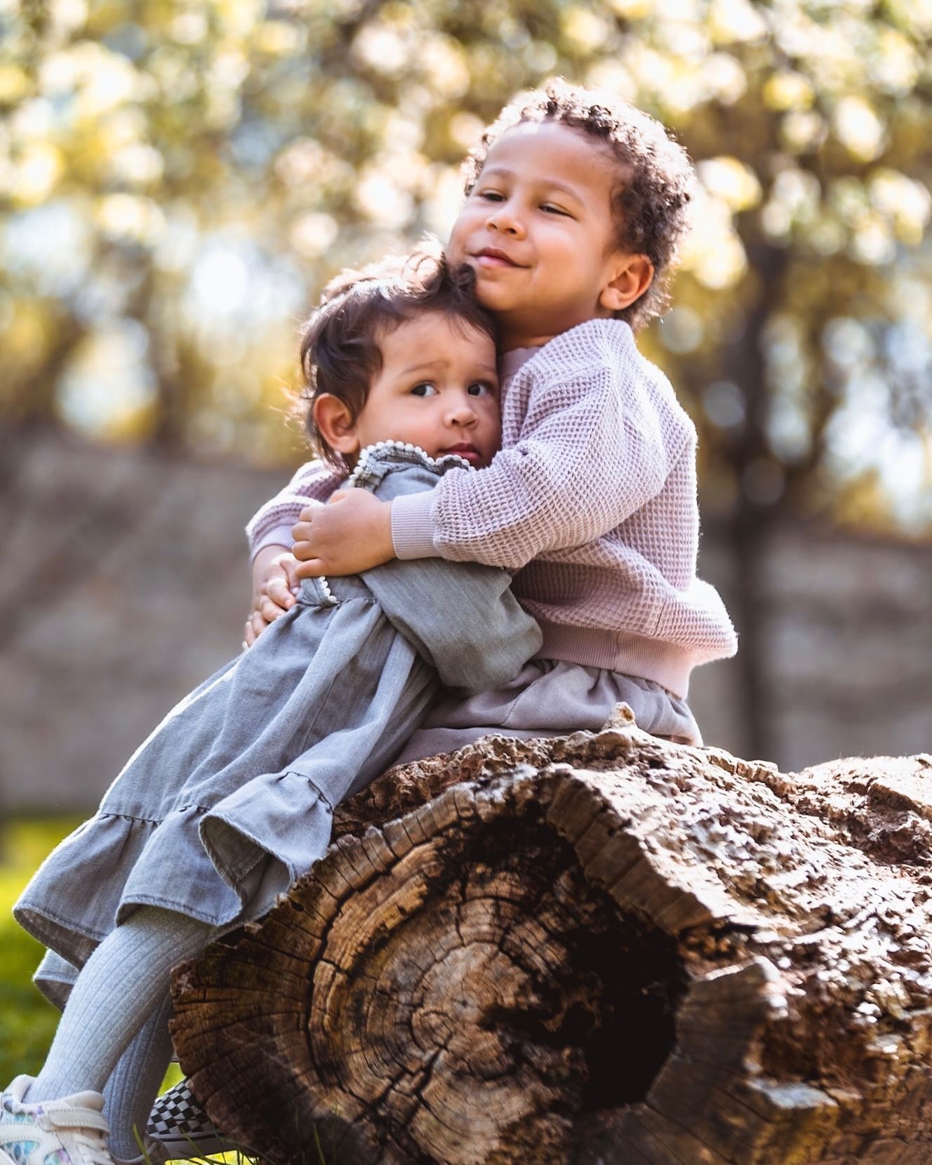 Two young siblings hugging outdoors